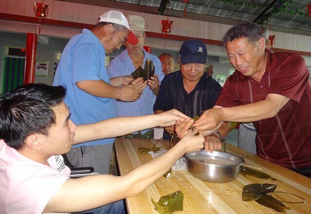 图为康复对象与父亲一同包粽子过节