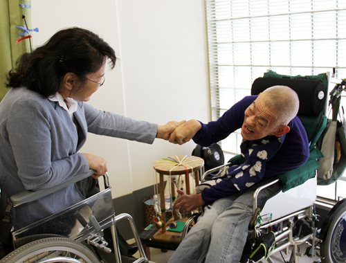 图为张海迪主席考察东京新宿区残疾人福利中心时与重度残疾人交谈
