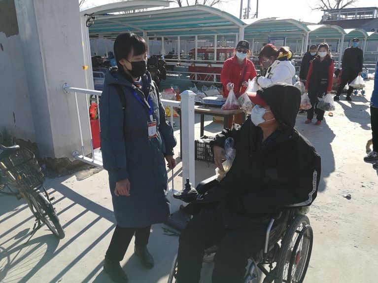 彭娜在菜市场巡查时遇到需要更换轮椅的残疾人