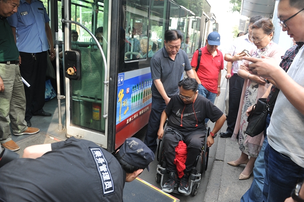 图为肢体残疾人体验乘坐公交车