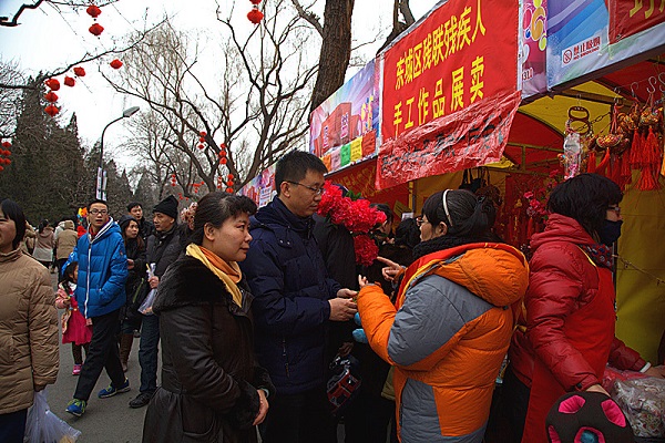 图为暴剑同志参观残疾人工艺品摊位