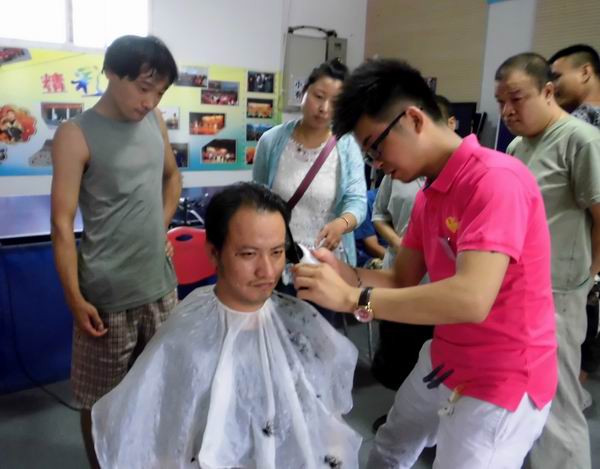 图为助残志愿者边为残疾人理发边传授理发技巧