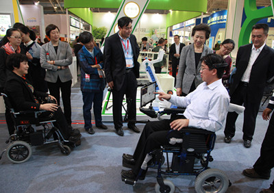图为：王乃坤理事长详细了解“脑电波轮椅”的性能和特点