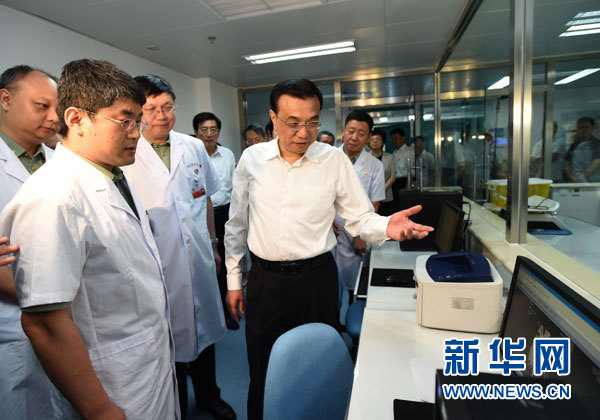 这是李克强向医务人员了解有关残疾孤儿治疗的情况。 新华社记者马占成摄