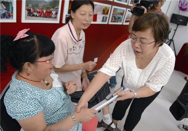 ▲8月28日，“乐动心灵、文化共享”智障人音乐理疗活动启动仪式在花家地南里温馨家园举行。图为音乐老师指导残疾人使用乐器进行康复训练。 贾  宁/摄