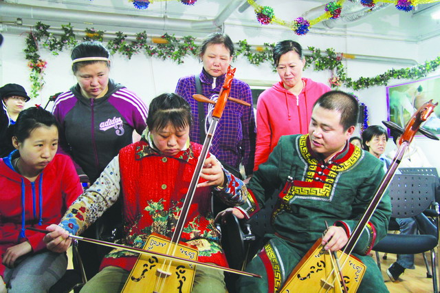 ▲4月19日，市残疾人活动中心、中国音乐治疗学会等共同举办的“乐动心灵、文化共享”智障人音乐理疗启动仪式正式举行。图为老师正在教智障朋友学习马头琴。刘毅彬摄